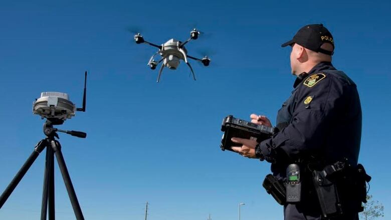 An Ontario Provincial Police officer is pictured operating a drone on a sunny day.