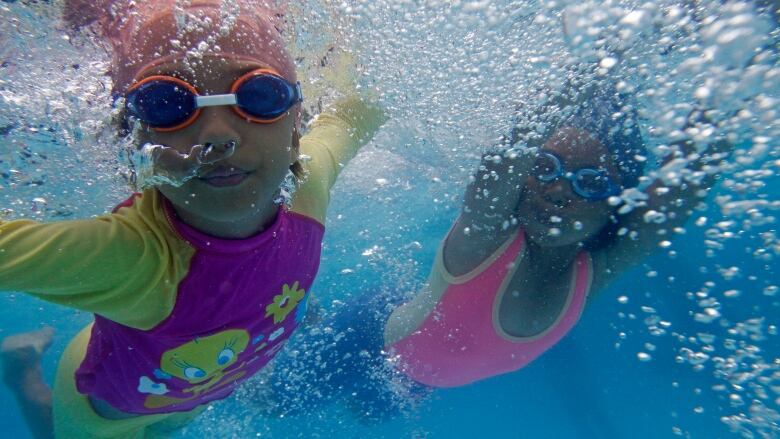 Two little girls swimming underwater at a pool