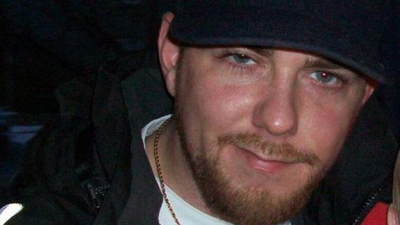 A young bearded man wears a baseball cap