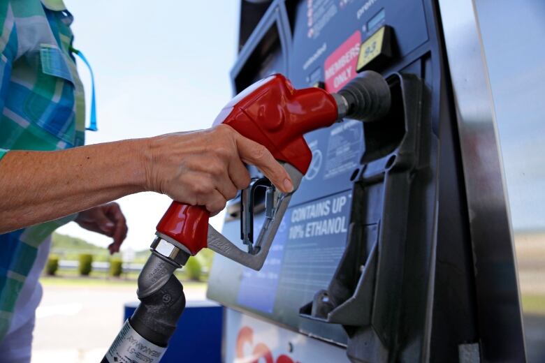 Woman lifting nozzle off gas pump.