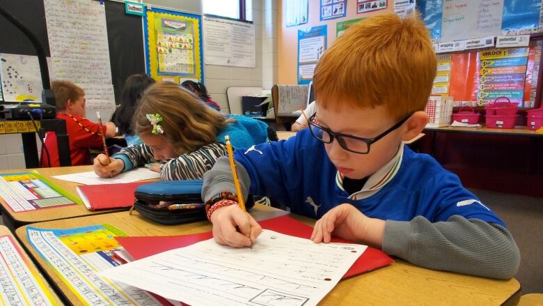 An elementary aged student does work at a desk