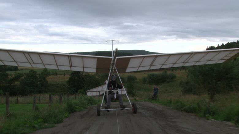 A man sitting in a glider/plane in a field.