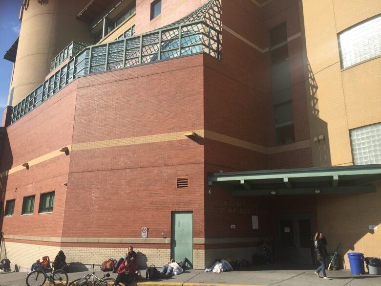 A photo from outside the Drop-In Centre where people are sitting in the sun. 