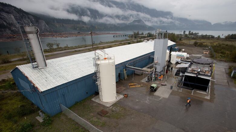 A large rectangular building with blue siding is pictured, with the sea next to it.