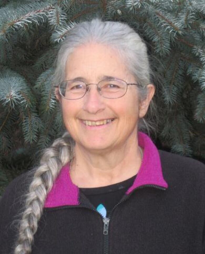 A smiling woman with her hair tied in a long, grey braid.