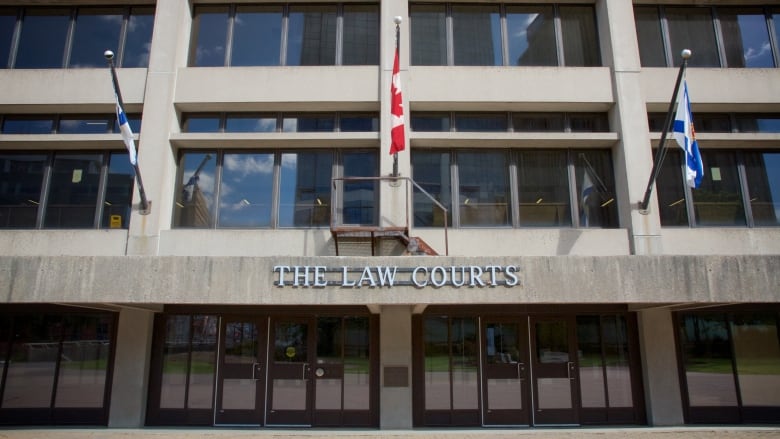 The sign at the front of the Law Courts on Upper Water Street in Halifax is seen with three flags above it.