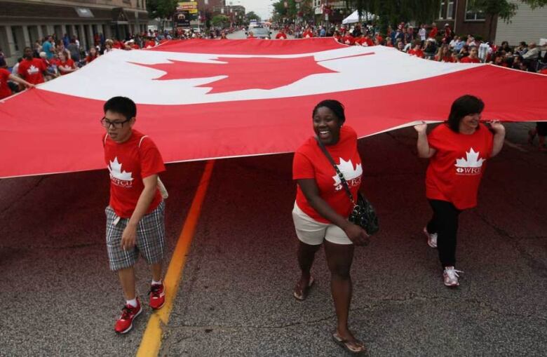 A group carries a giant Canada flag.