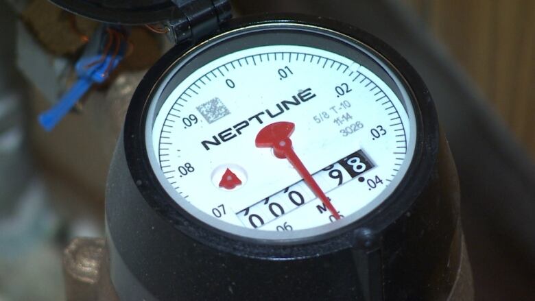 A closeup shows the dial of a water meter.