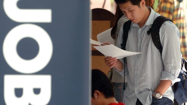 A man looks at a job ad at a job fair.