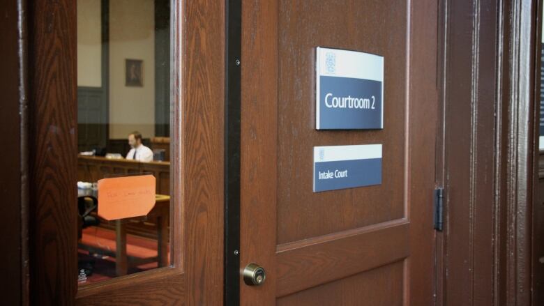 A wooden door with a sign that says 'Courtroom 2' is shown.