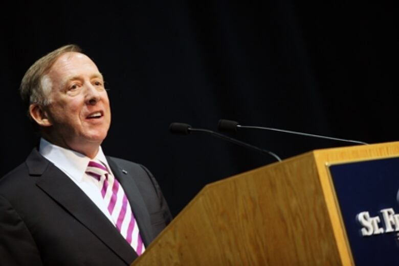 Former St. Francis Xavier University president Sean Riley seen at a wooden podium.