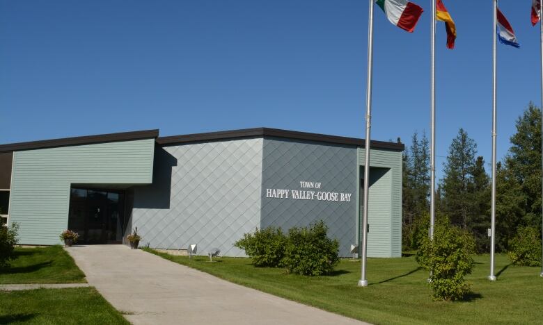 Modern light green building with flag poles in front of it