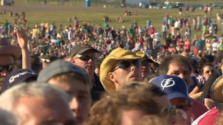 A crowd of people with one man in a cowboy hat. 