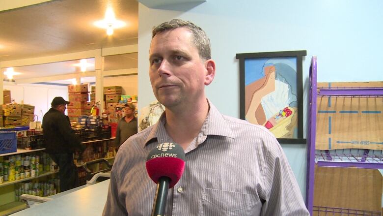 Mike MacDonald standing in front of shelves of food 