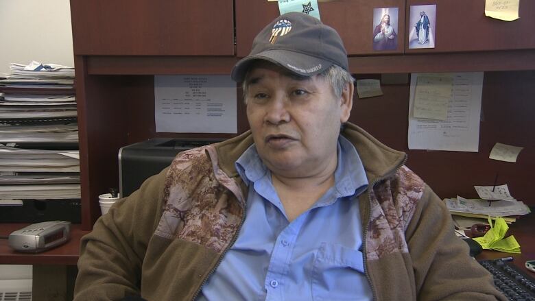 A man wearing a baseball cap stares forward.