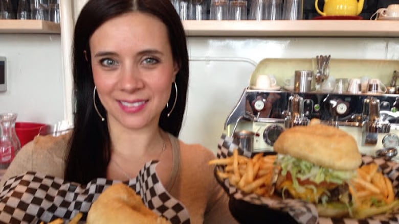 A woman holds burgers. 