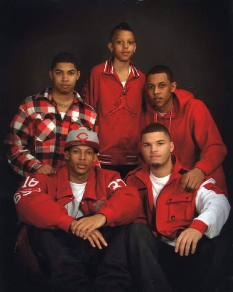 A family photo including five young Black men all wearing red clothing