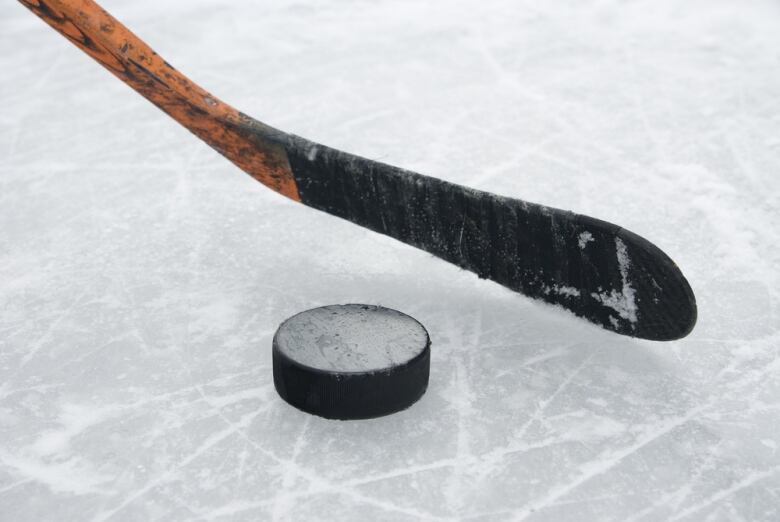 A hockey stick and puck is seen on ice.