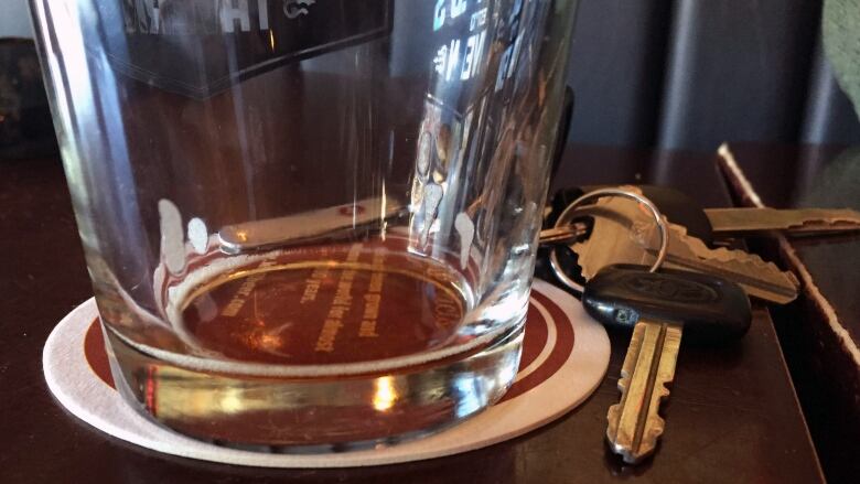 An empty glass and keys on a table. 