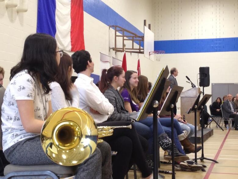 Band students ready to perform in a school gymnasium.