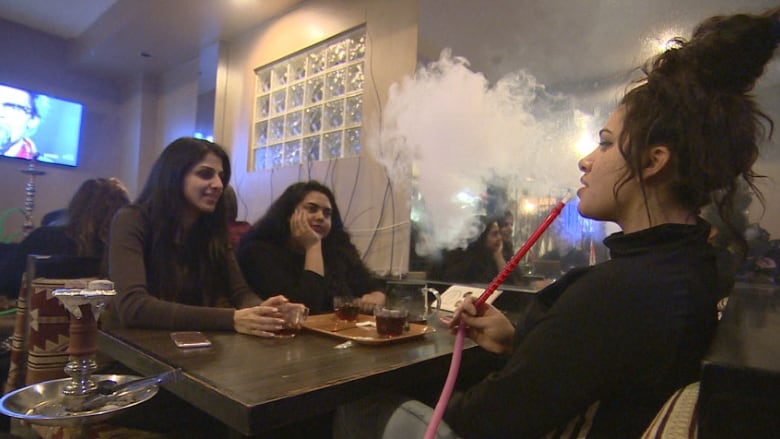 People are sitting in a room smoking from hookahs.