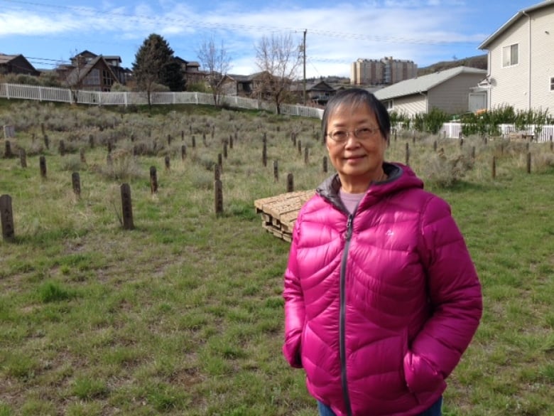 A woman in purple down jacket stands in a cemetery.