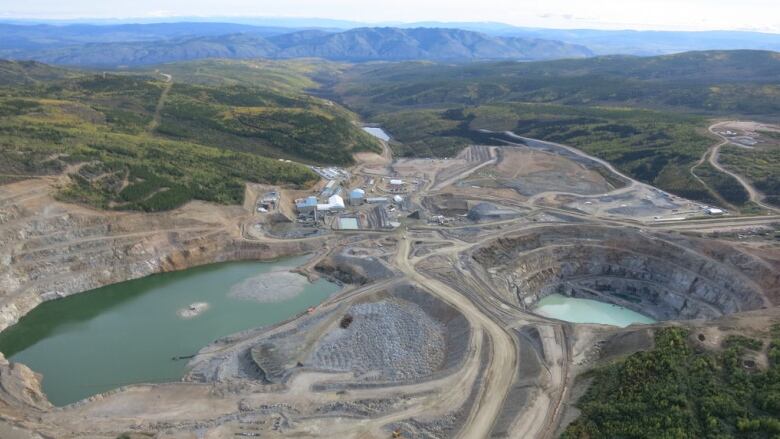 An aerial view of a mine, with tailings ponds, roads and buildings visible.