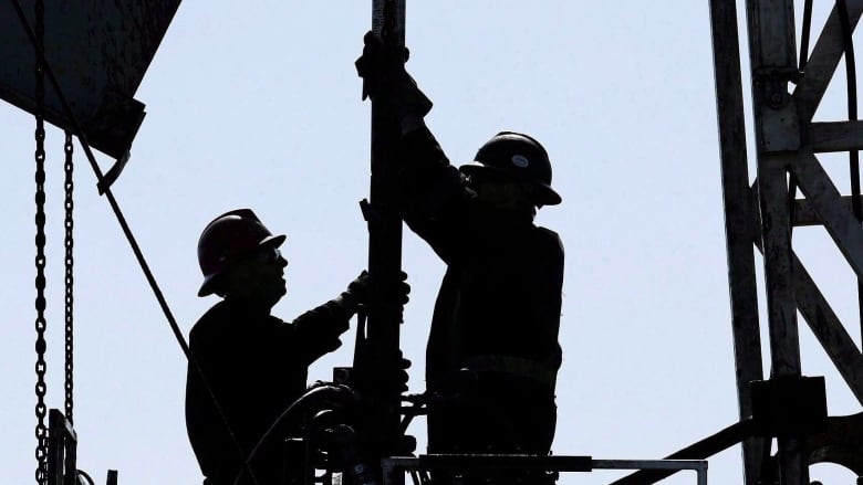 Two oil workers in a silhouette. 