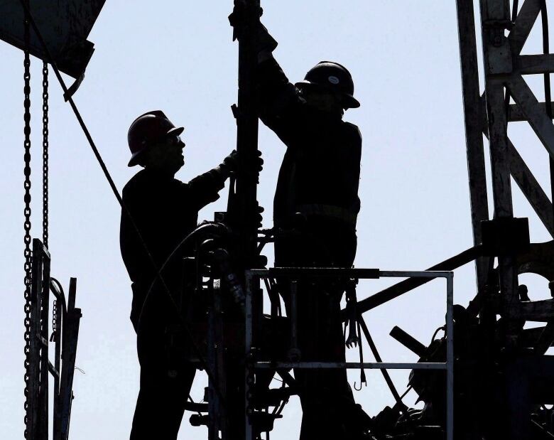 Two oil workers in a silhouette. 