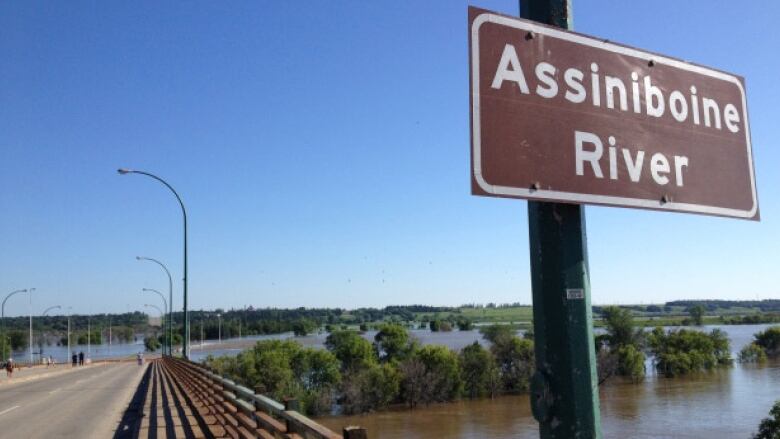 A sign that says 'Assiniboine River' is pictured.