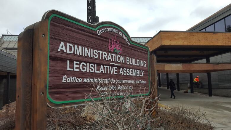 A wooden sign that says Government of Yukon - Administrative Building - Legislative Assembly.