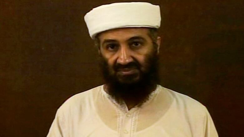 A bearded man in a white hat and shirt.