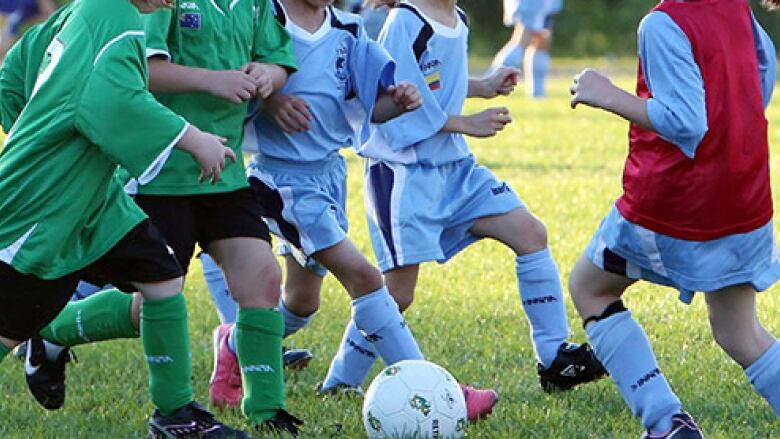 Children playing soccer on a grass pitch.