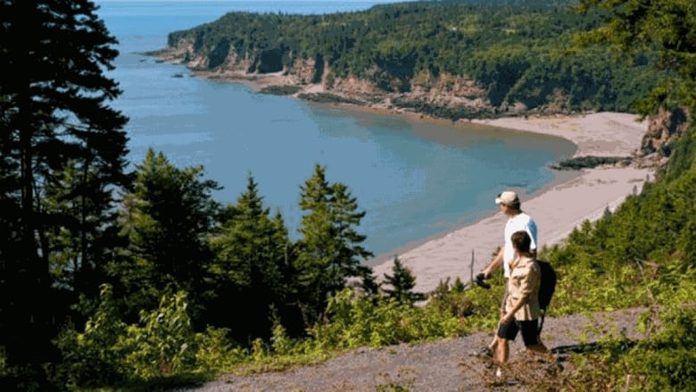 A couple hike in front of a vista