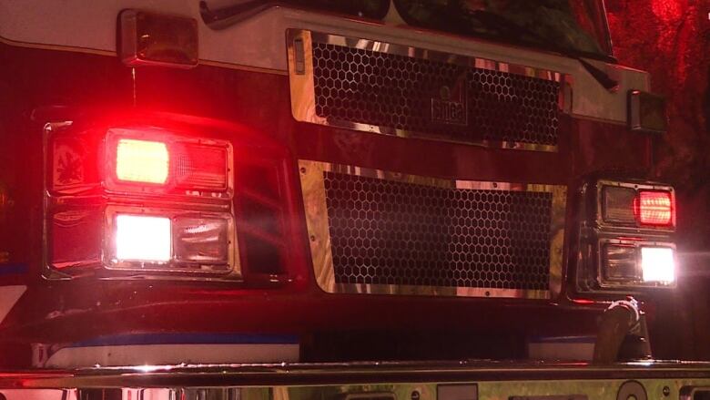 A closeup shows flashing red lights on the front of a fire truck.