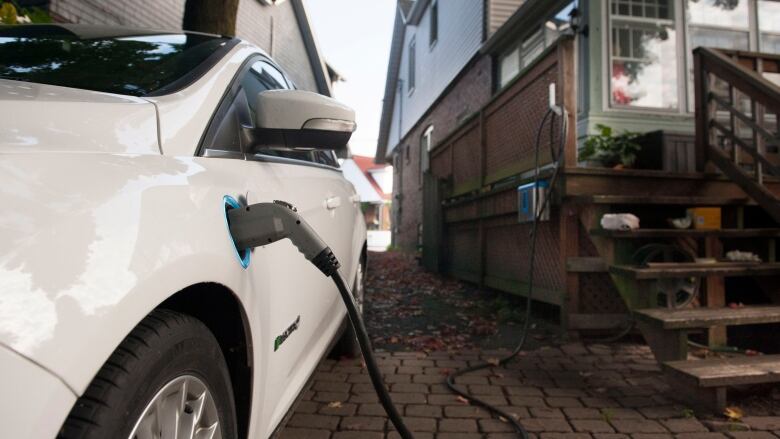 A white electric car charges in a driveway.