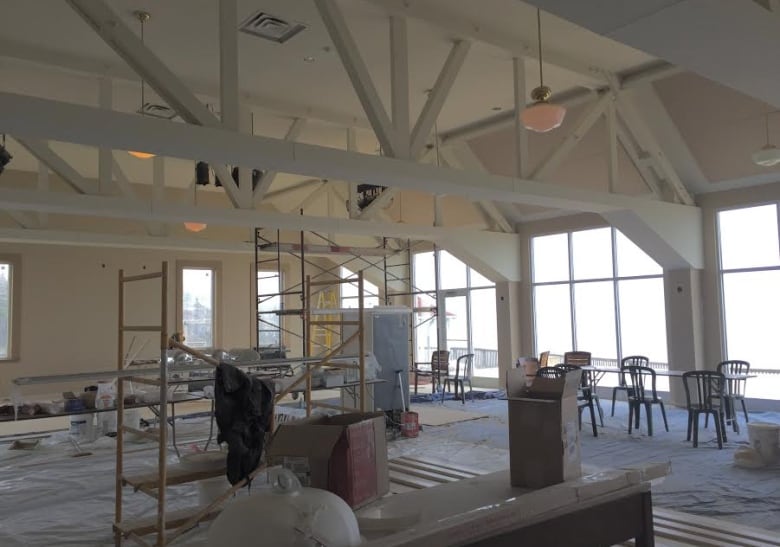 Scaffolding and work materials are shown inside a white room with tall windows.