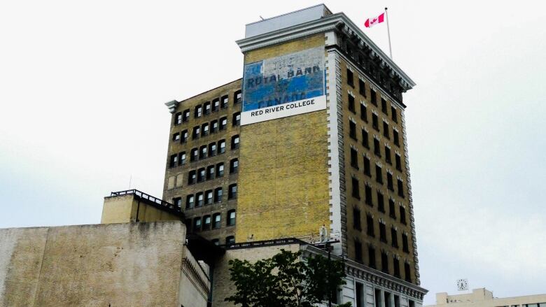 The side of a tall concrete building in Winnipeg is seen with a faded, painted sign on the side, saying Royal Bank of Canada.