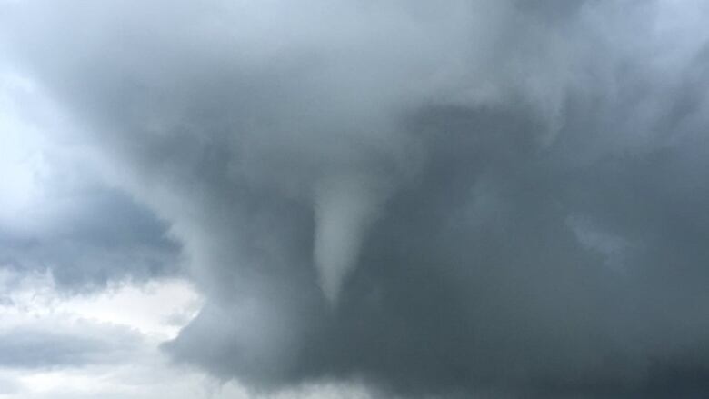 A funnel cloud is shown in a dark sky.