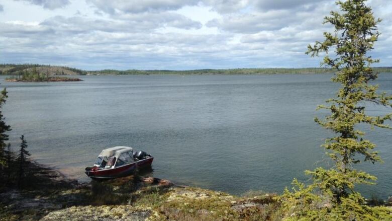 A boat sits on a lake shore.