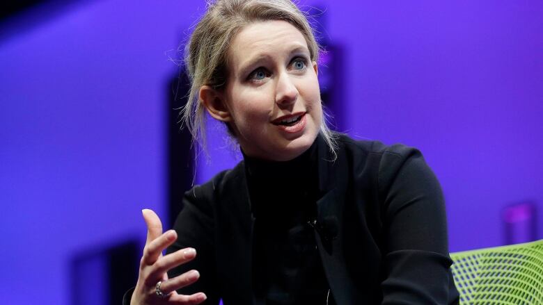 A woman wearing a black outfit speaks at a conferene.