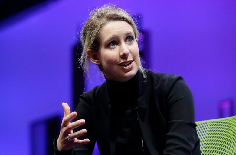 A woman wearing a black outfit speaks at a conferene.