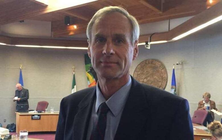 A man in a suit in council chambers. 