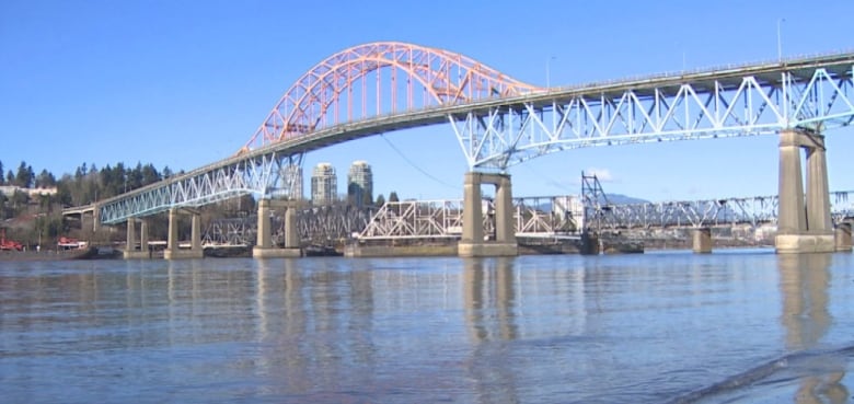 A bridge with orange tresses above a river.