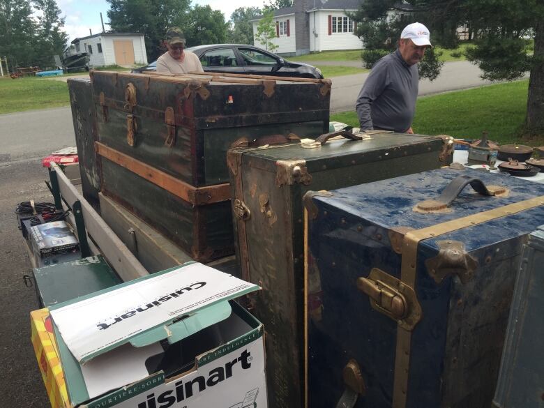 Old trunks are stacked in the driveway of a home.