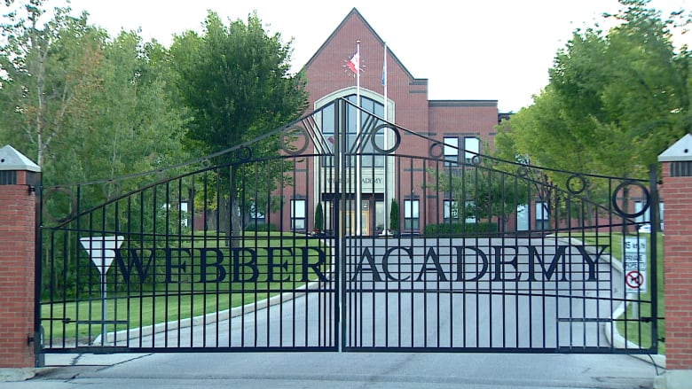 A brick school behind a fence that reads 