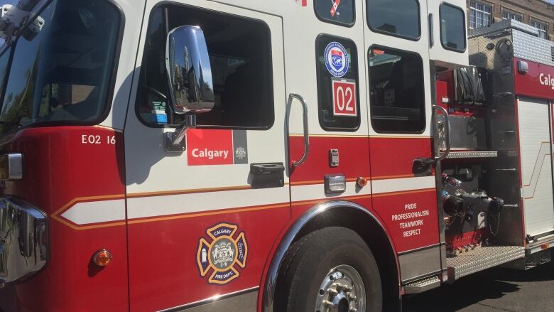 A closeup view of a red Calgary fire truck looking at the driver side door.