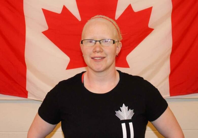 A woman stands in front of a Canadian flag