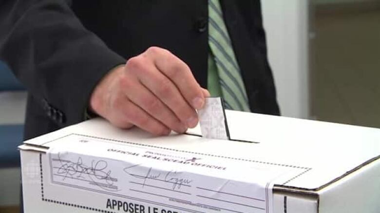 A person places a ballot in a box