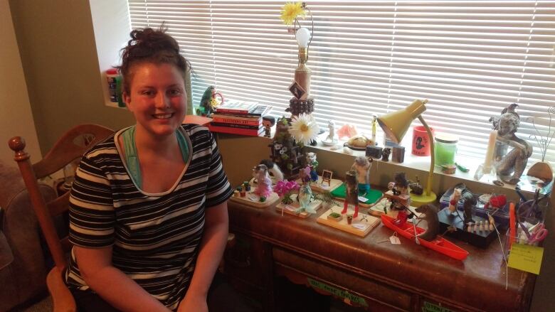 A woman smiles next to a row of taxidermied rats.